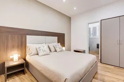 a white bedroom with a large bed and a sliding glass door at San Pietro Vatican Apartments in Rome