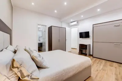 a white bedroom with a large bed and a tv at San Pietro Vatican Apartments in Rome