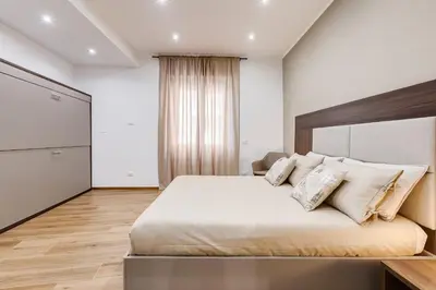 a bedroom with a large bed with white sheets and pillows at San Pietro Vatican Apartments in Rome