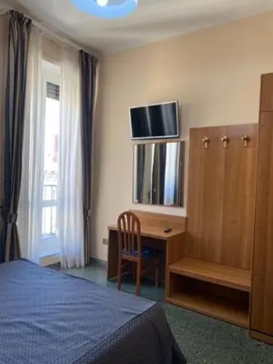 a bedroom with a bed and a desk and a television at Guest House Pitagora in Rome