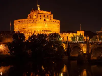 a bridge over a river with a city at night at Alto Apartment in Rome