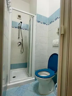 a bathroom with a blue toilet and a shower at h135 in Rome