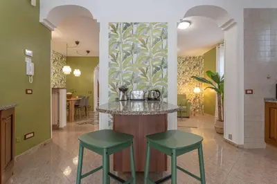 a kitchen with a island with two green stools at BBHOME Domus aquae inside of appia antica park in Rome