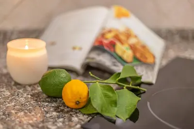 a candle and lemons on a counter with a book at BBHOME Domus aquae inside of appia antica park in Rome
