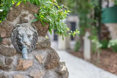 a statue of a lion head on a stone wall at BBHOME Domus aquae inside of appia antica park in Rome