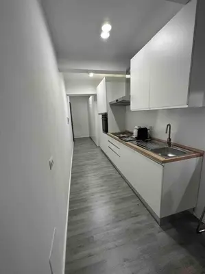 a kitchen with white cabinets and a wooden floor at Cozy design studio apartment in Porta Maggiore. in Rome