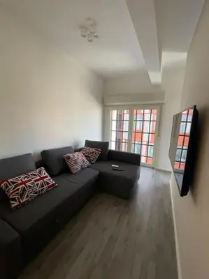a living room with a black couch and some windows at Cozy design studio apartment in Porta Maggiore. in Rome