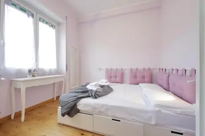 a white bedroom with a large bed with pink cushions at 4BNB - Trionfale Apartment in Rome