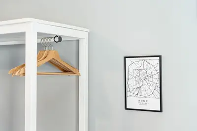 a white wardrobe with a picture on the wall and a shelf with shoes at Trastevere Guestrooms in Rome