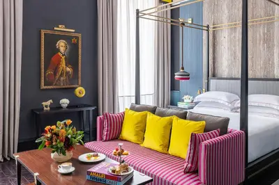 a bedroom with a bed and a couch with yellow pillows at Palazzo Roma - The Leading Hotels of the World in Rome