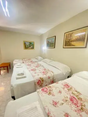 a hotel room with three beds and a couch at Hotel Resi in Rome
