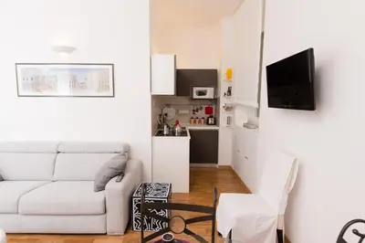 a white living room with a white couch and a kitchen at Baccina Inn in Rome