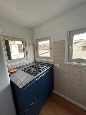 a kitchen with a stove and two windows at Manzoni Blue House by GHOR in Rome