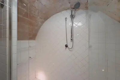 a shower in a white tiled bathroom at Fontanella Borghese CORI apartment in Rome