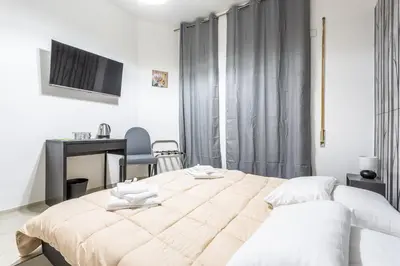 a white bedroom with a large bed and a desk at Ethnos Relais Vaticano in Rome
