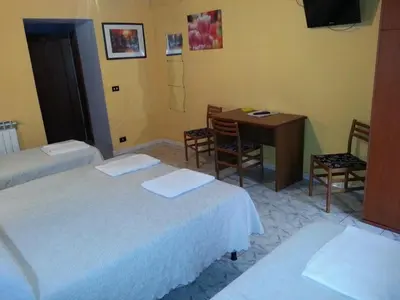 a room with two beds and a table and a desk at Roxena house in Rome