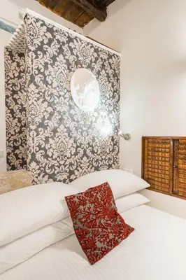 a white bed with a red pillow on top of it at Intimo ed Eclettico Studio a Trastevere in Rome