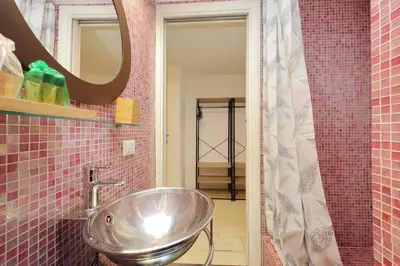a bathroom with a sink and a mirror and pink tiles at Flatinrome Trastevere 2 - Jacuzzi in Trastevere in Rome