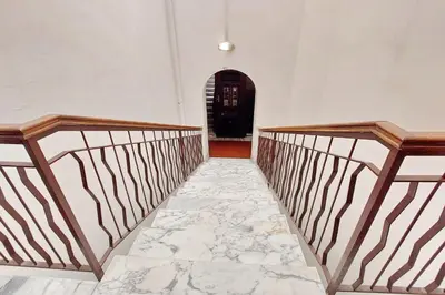 a hallway with a stone floor and stairs with a black door at Flatinrome Trastevere 2 - Jacuzzi in Trastevere in Rome