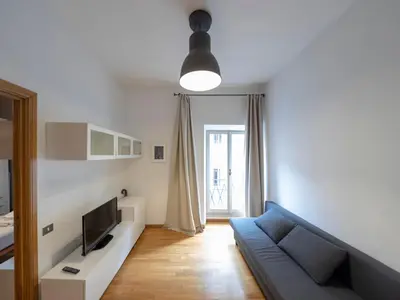 a living room with a blue couch and a television at Spanish Steps, Suite Dominic, Strollingrome in Rome