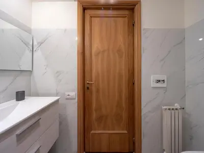 a bathroom with a wooden door next to a sink at Spanish Steps, Suite Dominic, Strollingrome in Rome