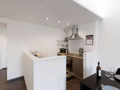 a kitchen with white walls and a table with a bottle of wine at Apartment Pratolina by Interhome in Rome