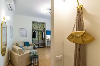 a living room with a couch and a purse hanging on a wall at 94Rooms Vatican Guest House - Vigliena in Rome
