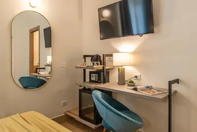 a room with a desk with a mirror and two blue chairs at 94Rooms Vatican Guest House - Vigliena in Rome