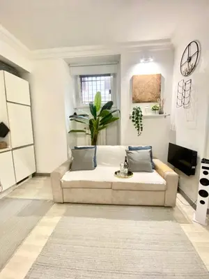 a white living room with a couch and a tv at “Suite Home Vaticano City” in Rome