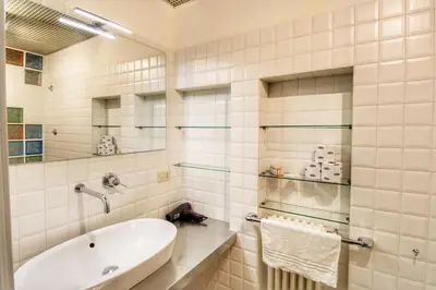 a white bathroom with a tub and a sink at Paglia45 Apartment at Trastevere by Yourhost in Rome