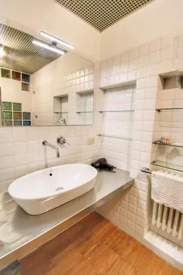 a white bathroom with a sink and a mirror at Paglia45 Apartment at Trastevere by Yourhost in Rome