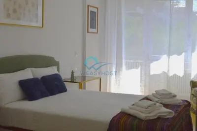 a bedroom with a white bed with blue pillows and a window at Oasis of Ample Space and Comfort in Rome