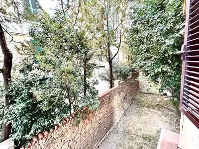 a brick wall with trees and bushes next to a building at Vatican home in Rome