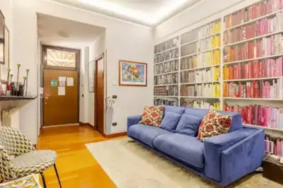 a living room with a blue couch in front of book shelves at Cristina's Home in Rome
