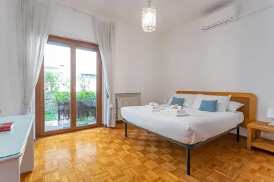 a white bedroom with a bed and a large window at St Peters Garden 3 BDR Apartment in Rome