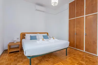a bedroom with a bed with white sheets and blue pillows at St Peters Garden 3 BDR Apartment in Rome
