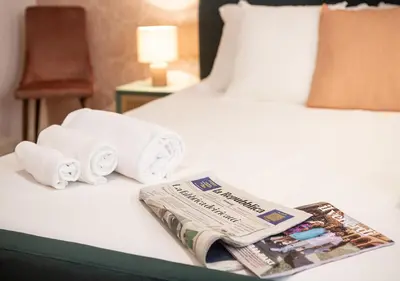 a bed with towels and a newspaper on it at Termini Alever apartament 3 bedrooms in Rome