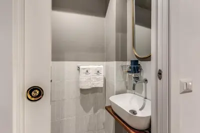 a white bathroom with a sink and a mirror at Margana Apartment - Maison D'art Collection in Rome