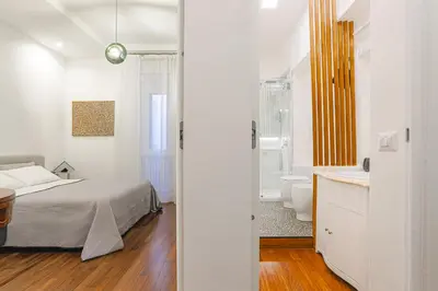 a white bedroom with a bed and a bathroom at Piazza Navona Deluxe Apartment - Piano 2 Roma in Rome