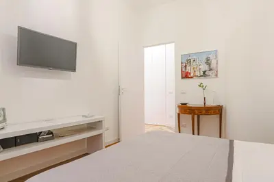 a white bedroom with a bed and a flat screen tv at Piazza Navona Deluxe Apartment - Piano 2 Roma in Rome