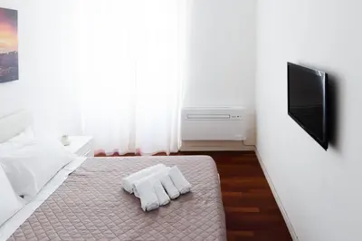 a bedroom with a bed with white sheets and a flat screen tv at EasySleep Vaticano in Rome