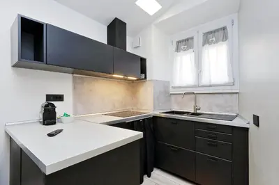 a kitchen with black cabinets and a white counter top at Diamond Apartments in Rome