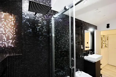 a bathroom with a black tiled shower and a sink at Diamond Apartments in Rome