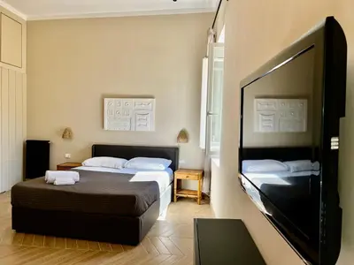 a bedroom with two beds and a flat screen tv at Trastevere Suite apartment in Rome