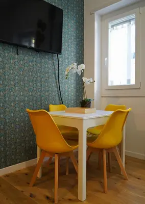 a dining room table with yellow chairs and a television at Santo Apartment in Trastevere in Rome