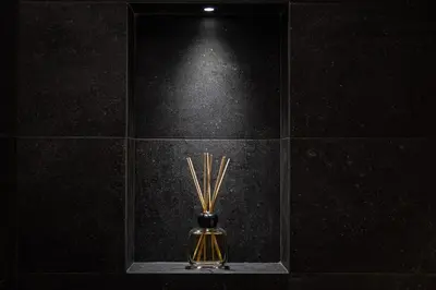 a glass vase with bamboo sticks in a black tile wall at San Pietro Guest House in Rome