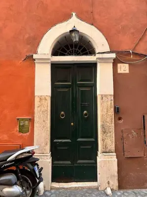 a green door in a red building with a motorcycle in front at Campo de’ Fiori Rooftop Apartment in Rome