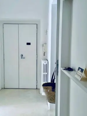 a white hallway with a door and a basket at Piazza di Spagna Home - Family Apartment in Rome