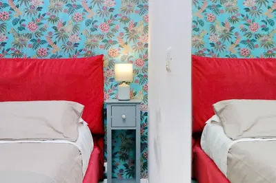 two beds in a room with red and blue wallpaper at Porta San Giovanni Suite in Rome