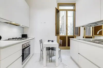 a kitchen with white counters and a white table and chairs at Opera Exclusive House by Premium Suites Collection in Rome